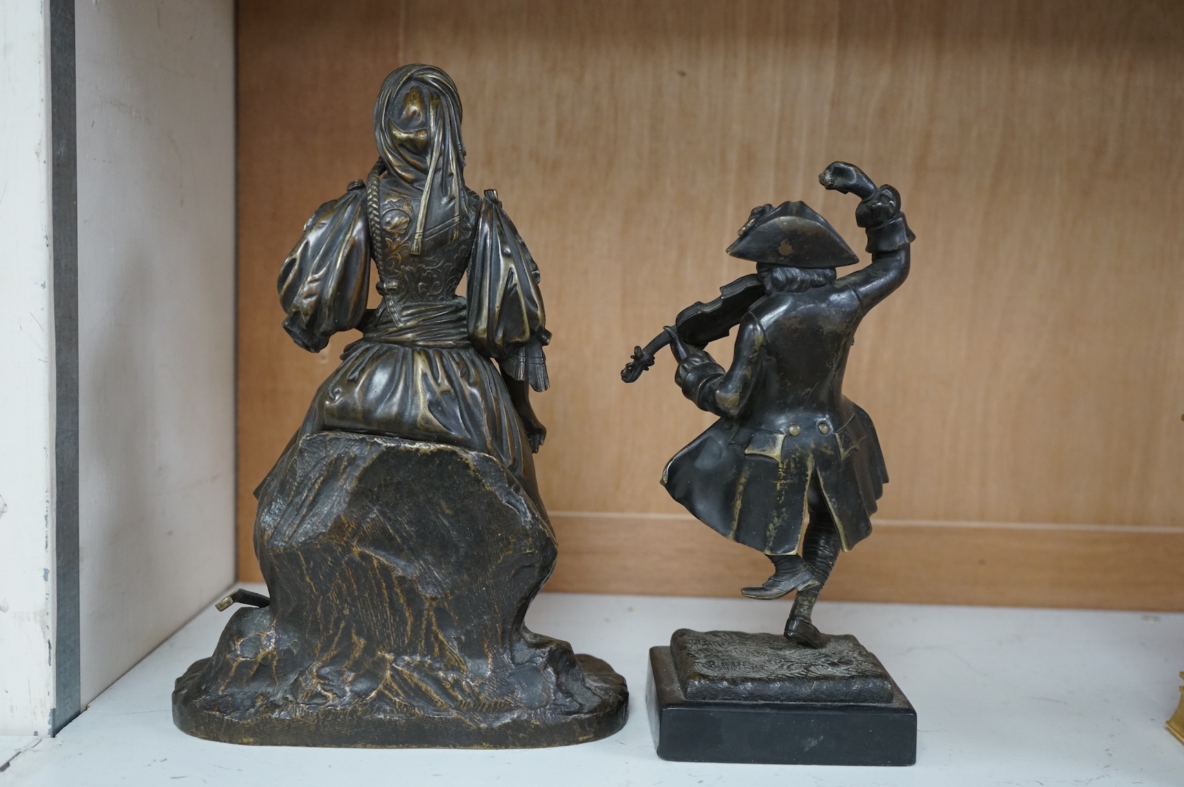 A small bronze figure of a male violinist and another bronze female figure with a lute against a rock, tallest 23cm high
